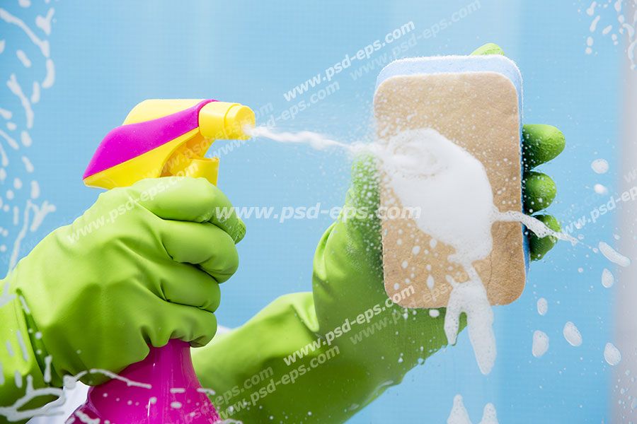 عکس با کیفیت نمایی از تمیز کردن شیشه با اسفنج و شیشه شوی توسط بانویی با دستکش پلاستیکی سبز رنگ