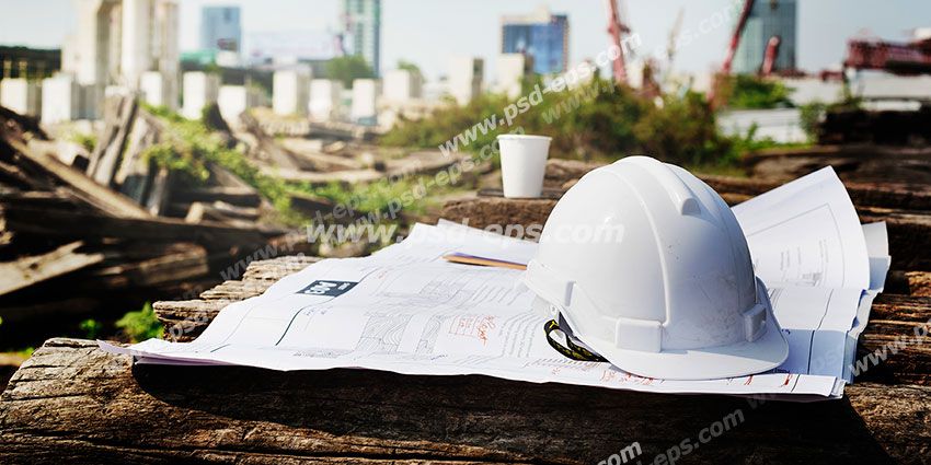 عکس با کیفیت تبلیغاتی کلاه ایمنی سفید بر روی نقشه های ساختمان و خانه ها در حال ساخت در نمای دور